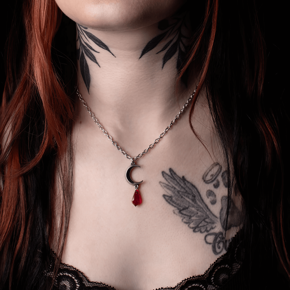 Gothic pendant necklace featuring a pewter crescent moon and red crystal drop, perfect for nighttime magic.