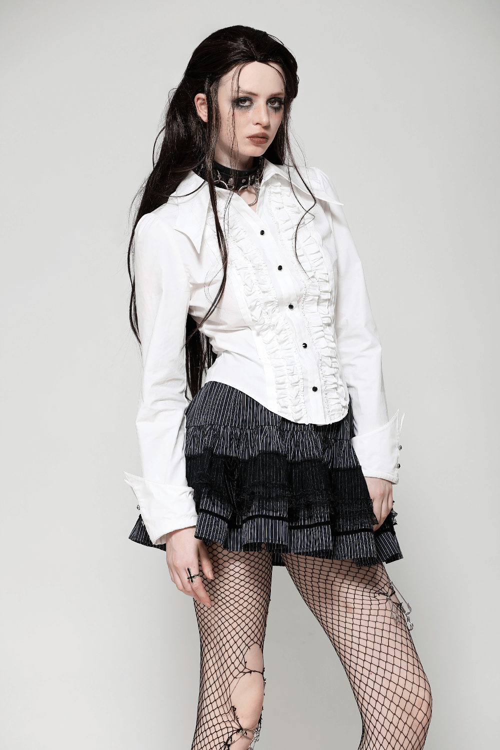 Model wearing a chic white ruffled shirt and a tiered striped skirt with lace, showcasing a stylish edgy look.