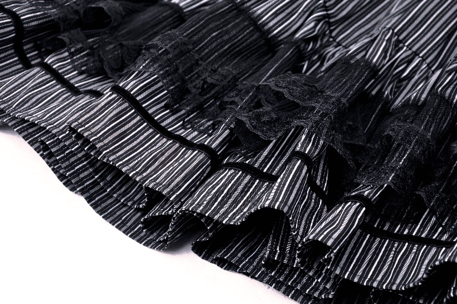 Close-up of a tiered striped skirt showcasing elegant lace details and playful ruffles in black and white.