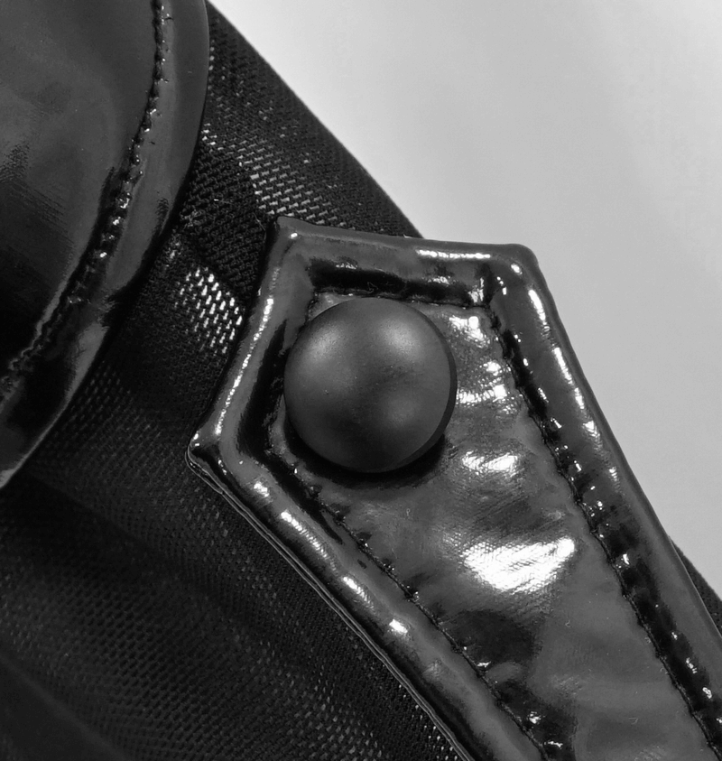 Close-up of glossy patent leather detail on a black mesh bodysuit, showcasing punk style and edgy design.