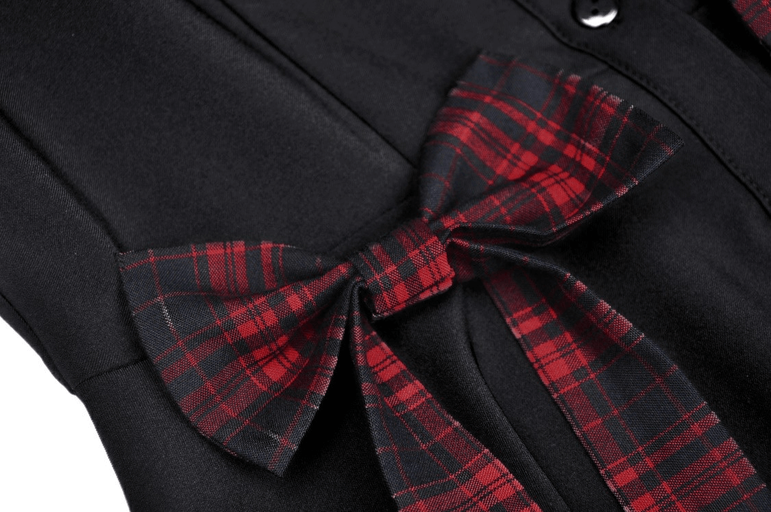 Close-up of a trendy black dress featuring a red plaid bow detail, showcasing stylish A-line silhouette.