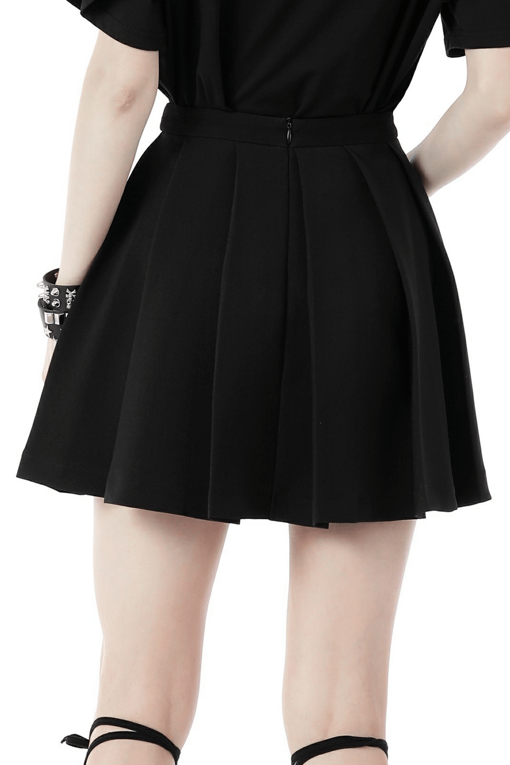 Back view of a trendy black pleated mini skirt highlighting its stylish design and elegant buckles.