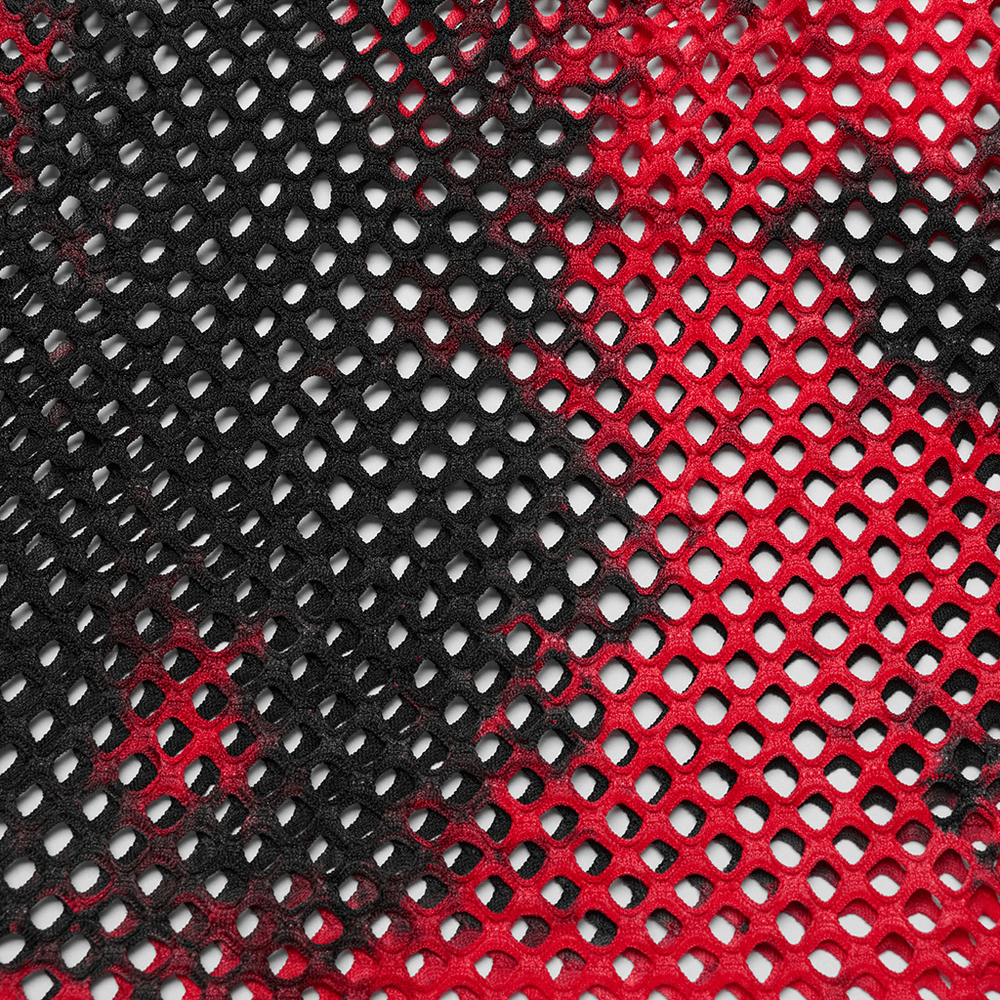 Close-up of trendy punk mesh fabric in bold red and black tie-dye pattern, perfect for an edgy T-shirt.