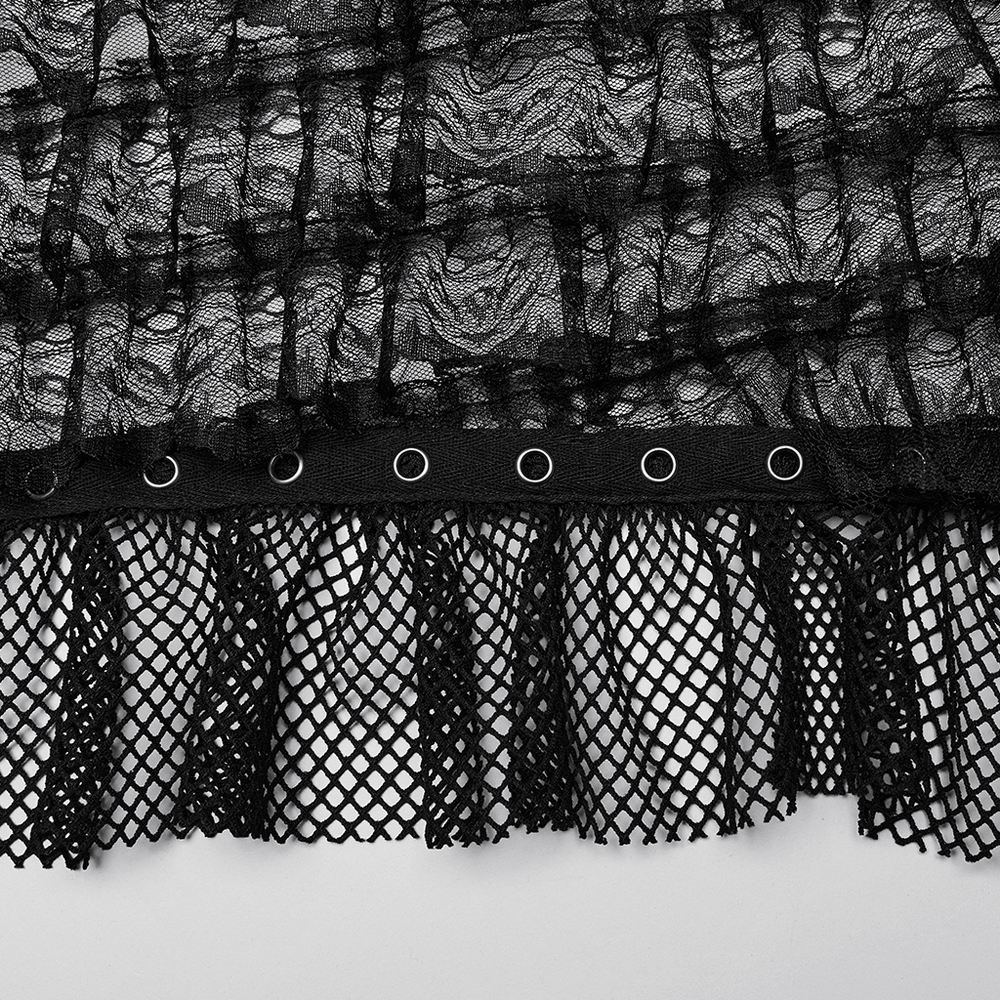 Close-up of black lace and mesh fabric with eyelets and fringe detailing for a gothic dress.