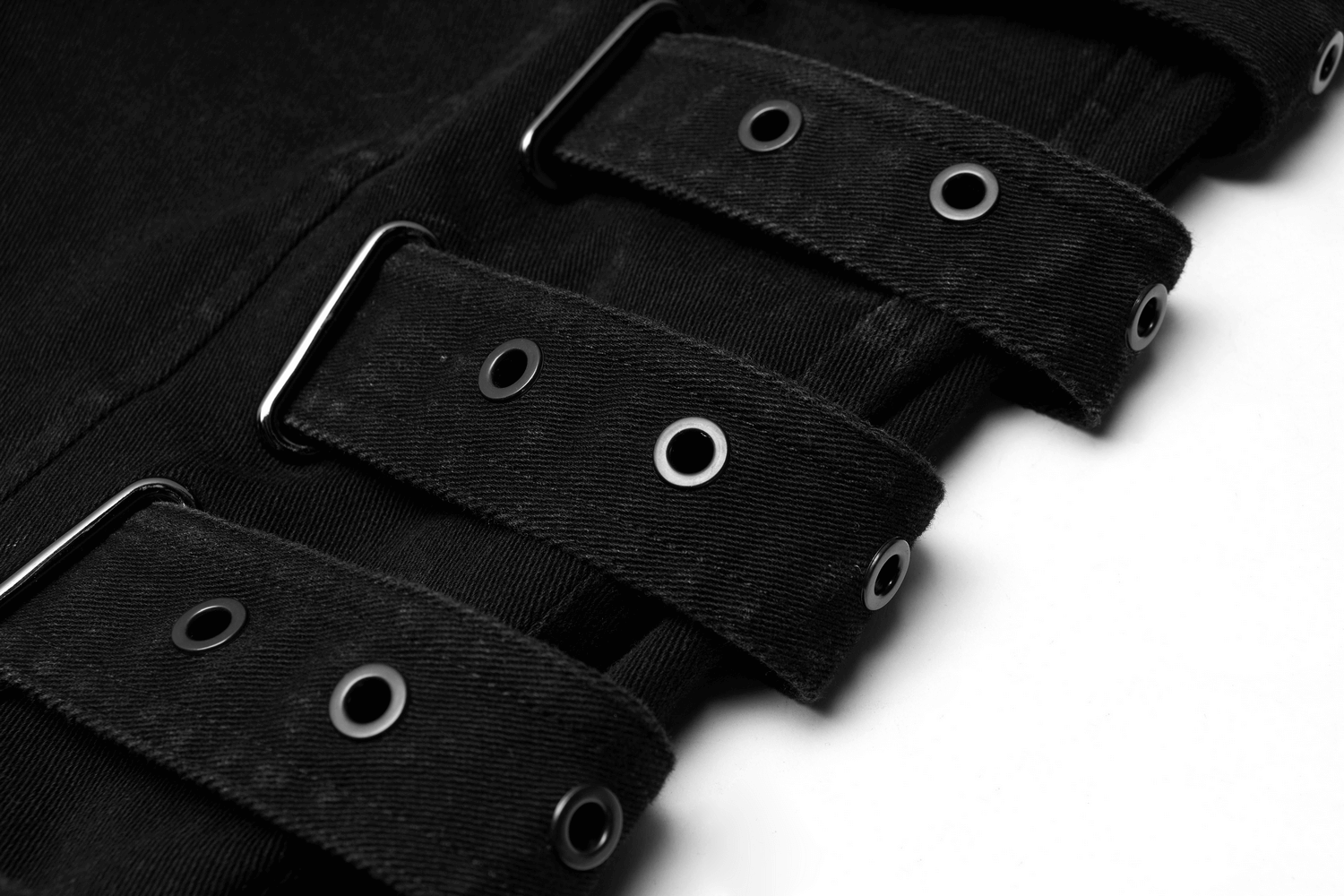 Close-up of black cargo trousers featuring stylish side oval grommets and strap detailing for an urban chic look.
