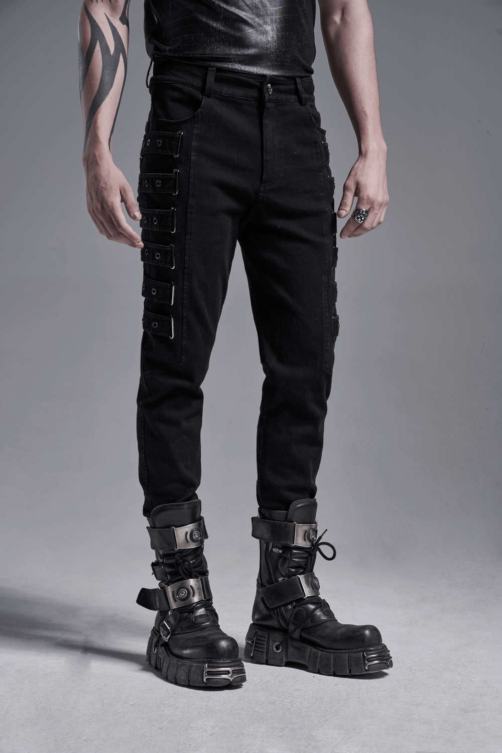 Urban black strap-detailed cargo trousers worn with bold black boots, showcasing a punk style and snug fit for a chic look.