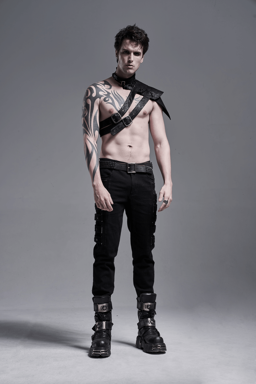 Stylish male model wearing urban black cargo trousers with unique side grommets and edgy accessories.