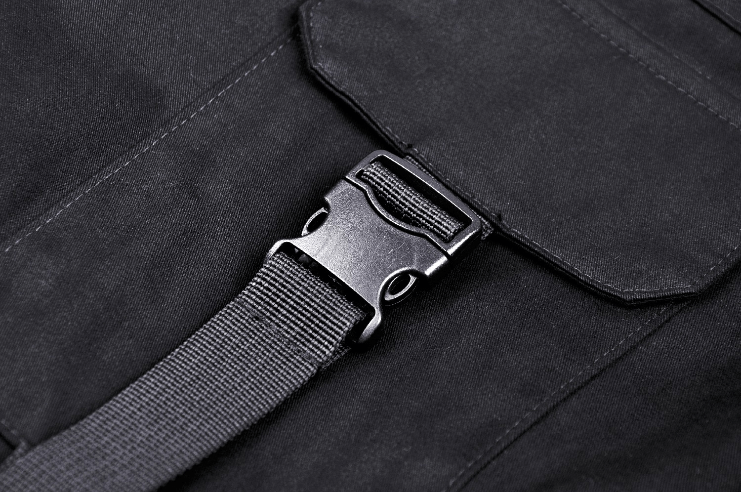 Close-up of black cargo pants buckle and strap detail, showcasing stylish design and adjustable features.
