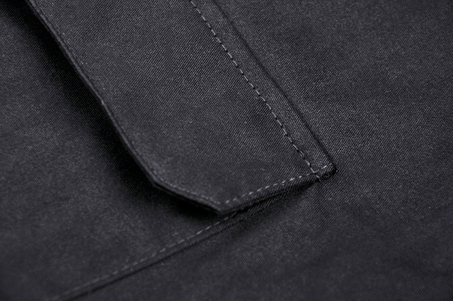 Close-up of urban-style black cargo pants fabric showcasing the pocket and stitching details.