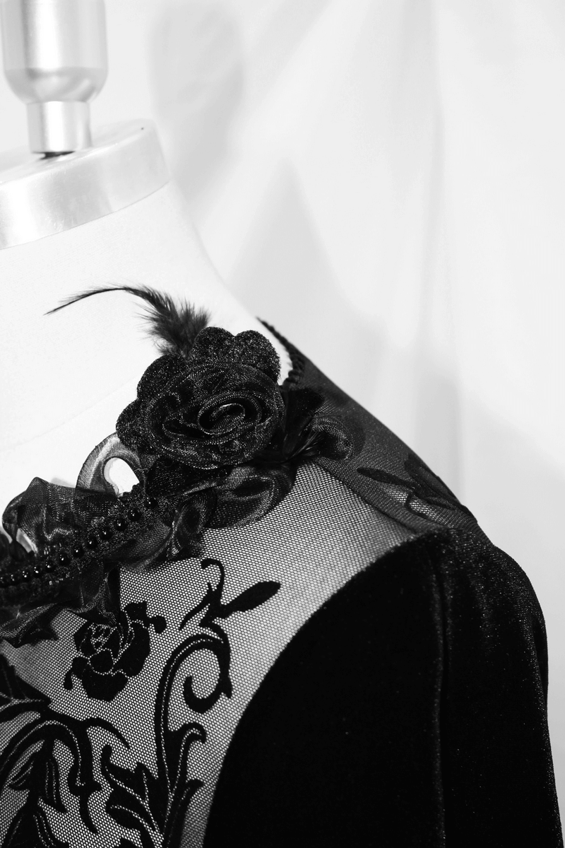 Close-up of velvet black dress featuring intricate filigree patterns and a decorative floral collar.