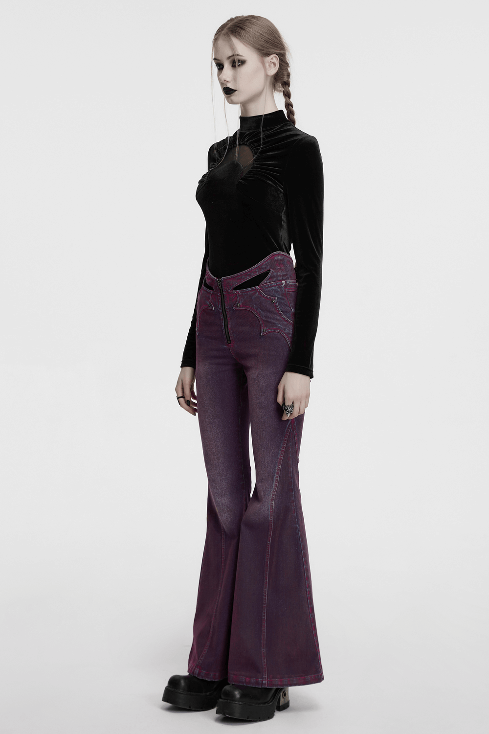 Model wearing a black velvet crescent cut-out top with flared purple jeans, showcasing edgy goth-inspired fashion.