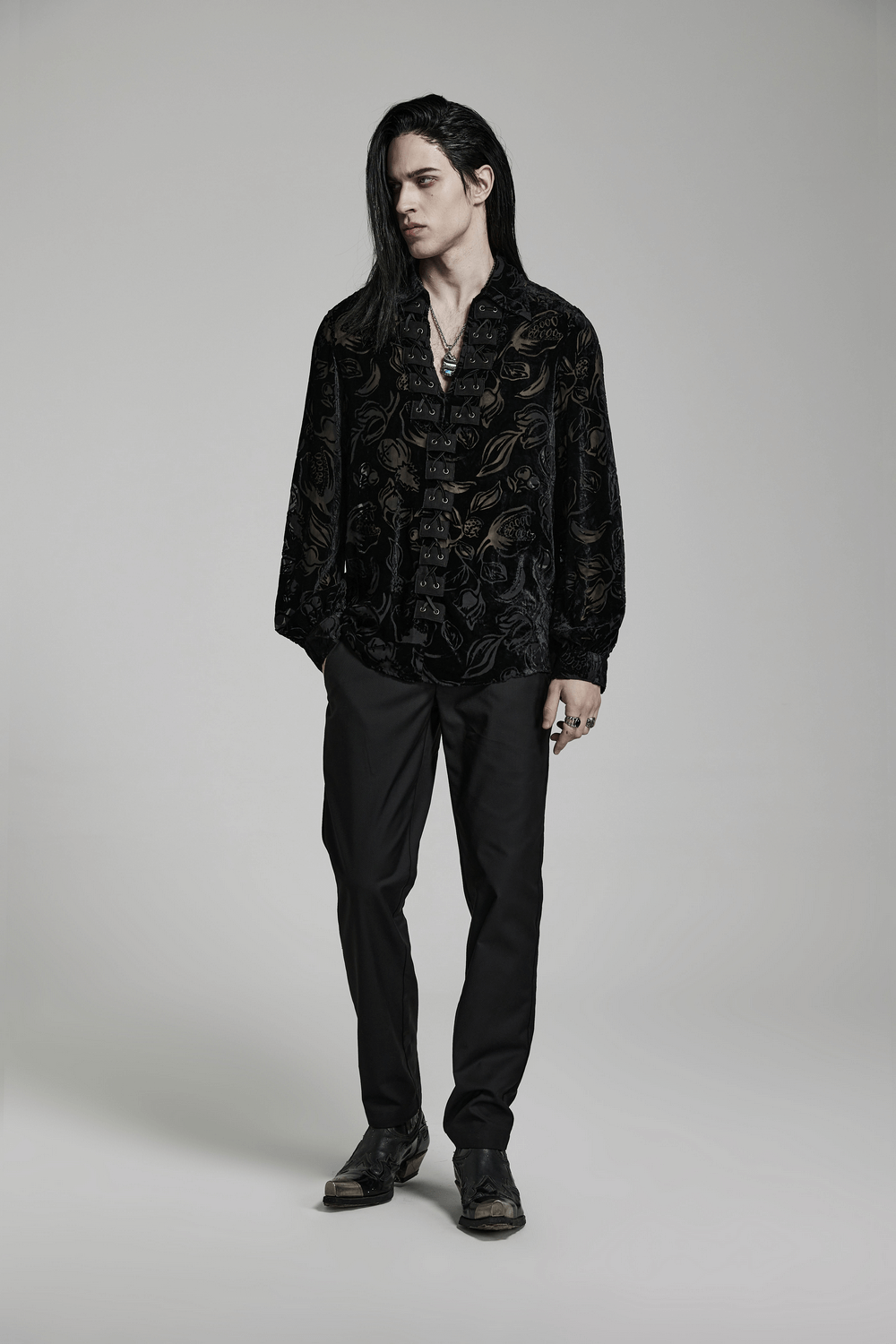 Stylish man in a velvet flocked Gothic shirt with piranha pattern and black pants, exuding Gothic elegance.