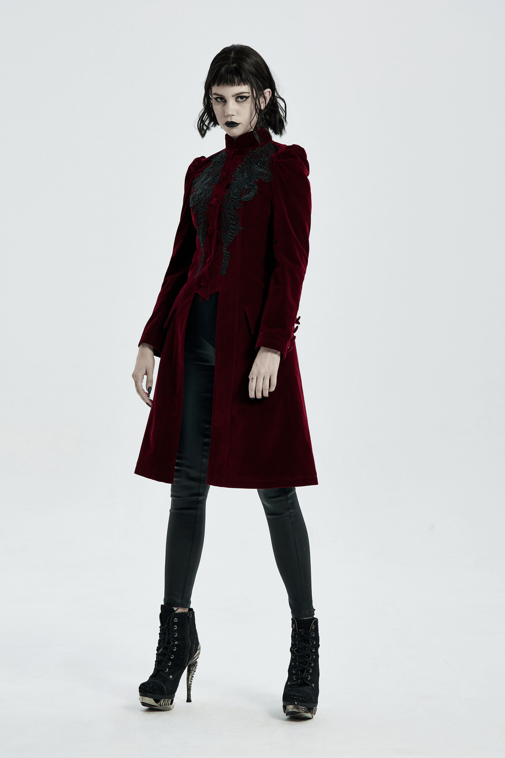 Gothic Victorian-inspired velvet coat with lace detail, showcasing a sleek silhouette on a model.
