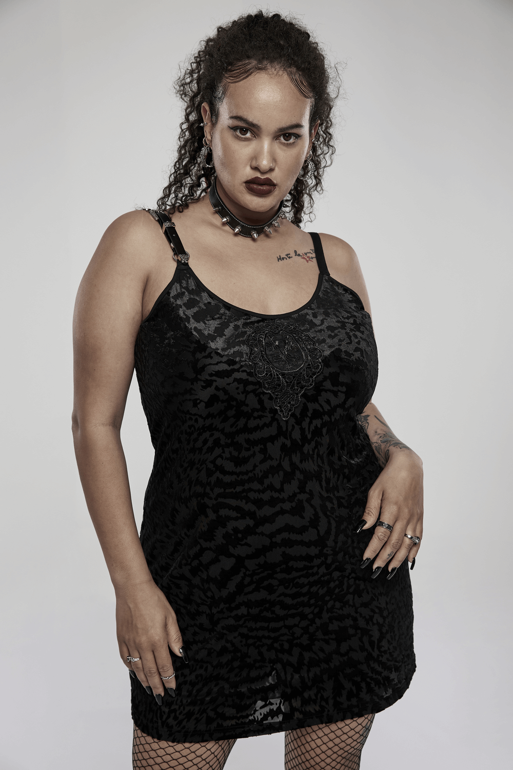 Model wearing a black velvet gothic dress with removable strap loop, showcasing an edgy and stylish look.