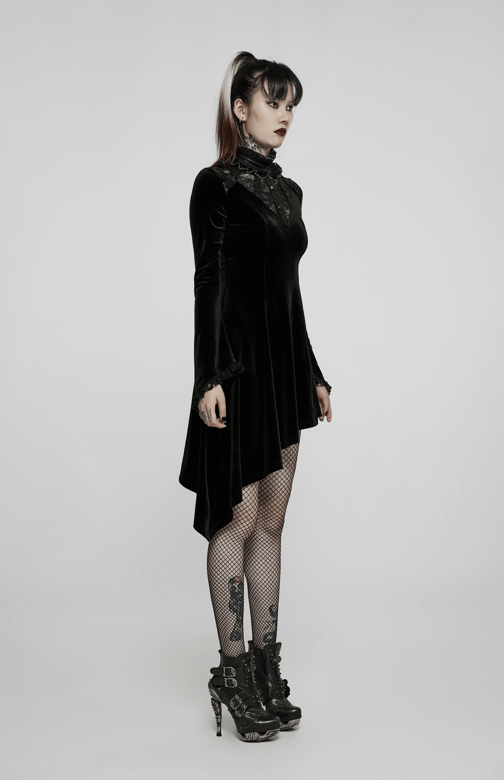 Elegant velvet Gothic dress with asymmetric hem and lace trim, paired with fishnet stockings and stylish boots.