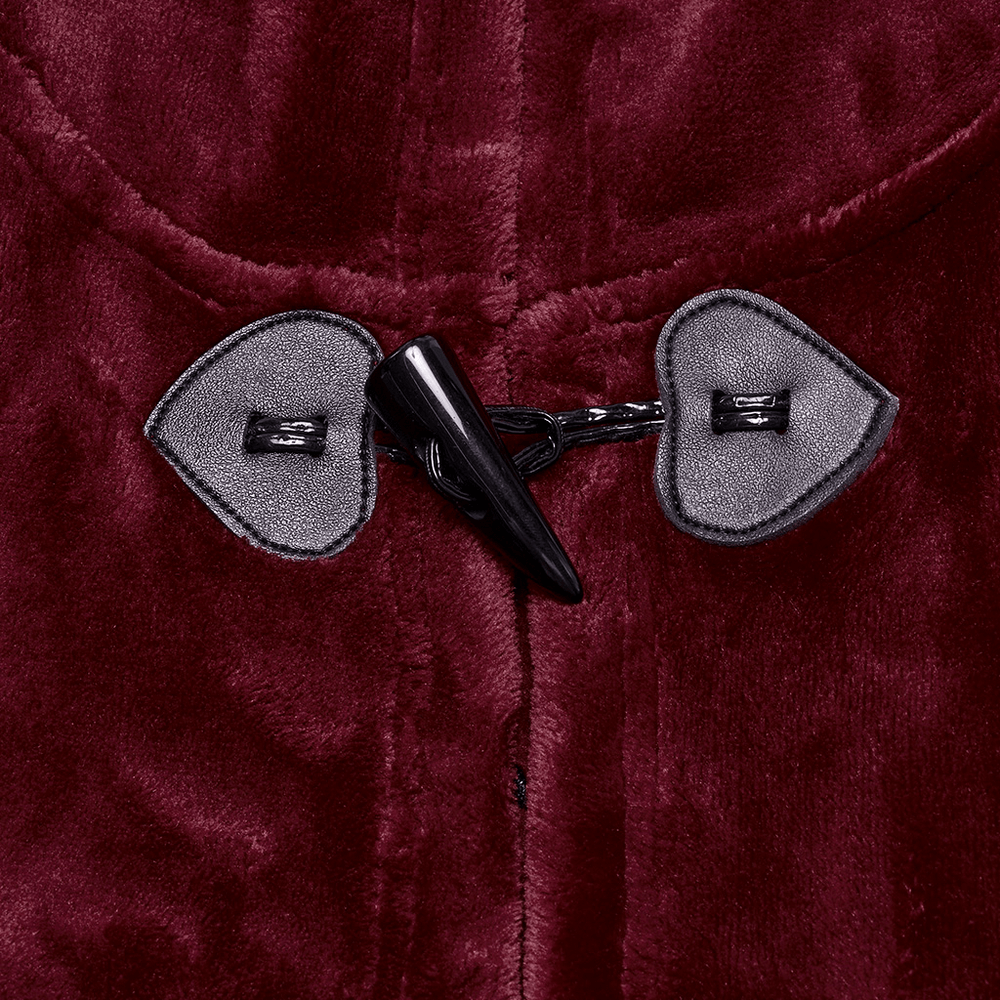 Close-up of dark velvet hooded cape clasp detail featuring unique heart-shaped buttons and a sleek black toggle.