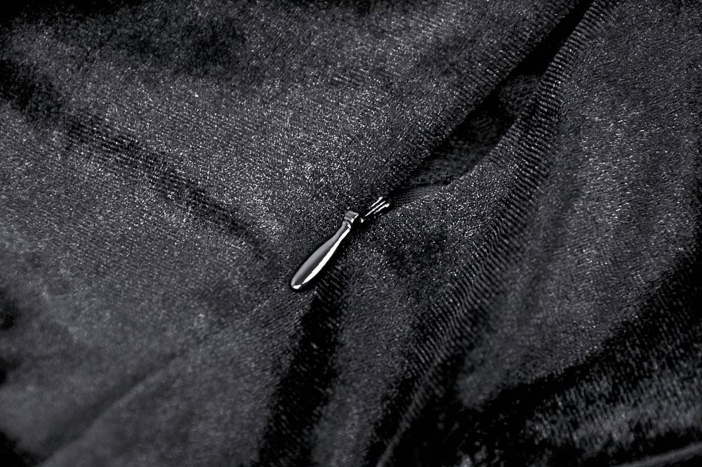 Close-up of elegant black velvet fabric featuring a detailed zipper pull on the gothic dress.