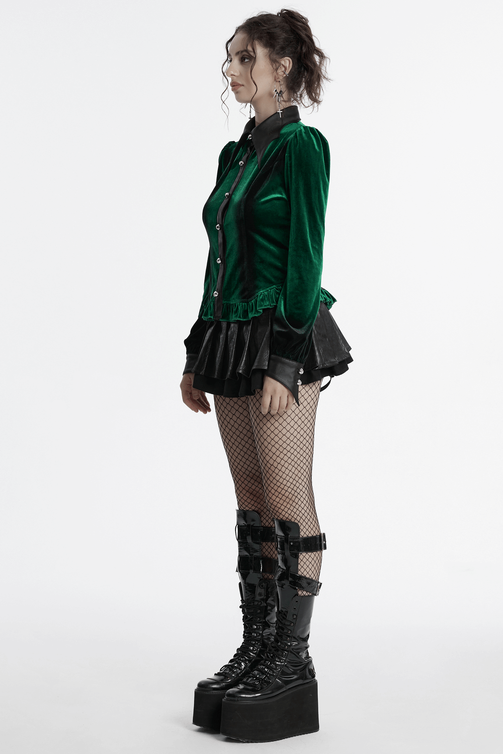 Gothic style model in green velvet lace-up shirt, ruffled skirt, and platform combat boots with fishnet stockings.