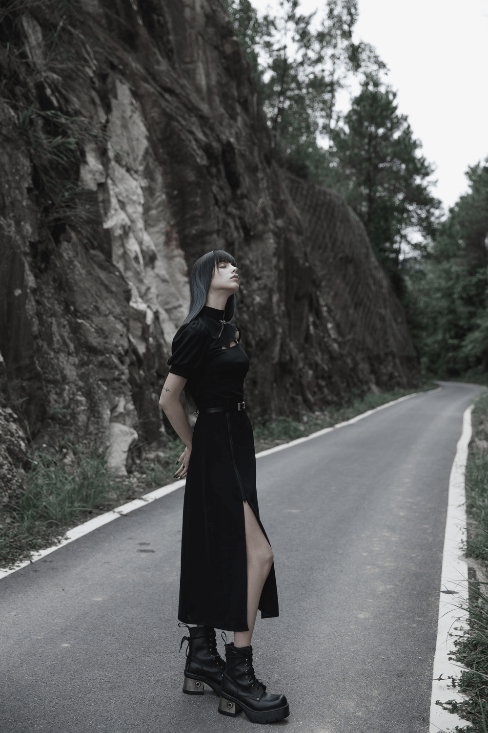 Model in black A-Line midi skirt with side zipper detail, showcasing a stylish silhouette on a scenic road.