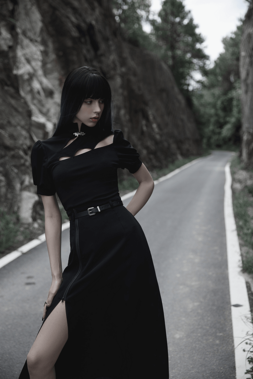 Chic model in an elegant black A-line midi skirt with stylish side zipper detail on a scenic road.