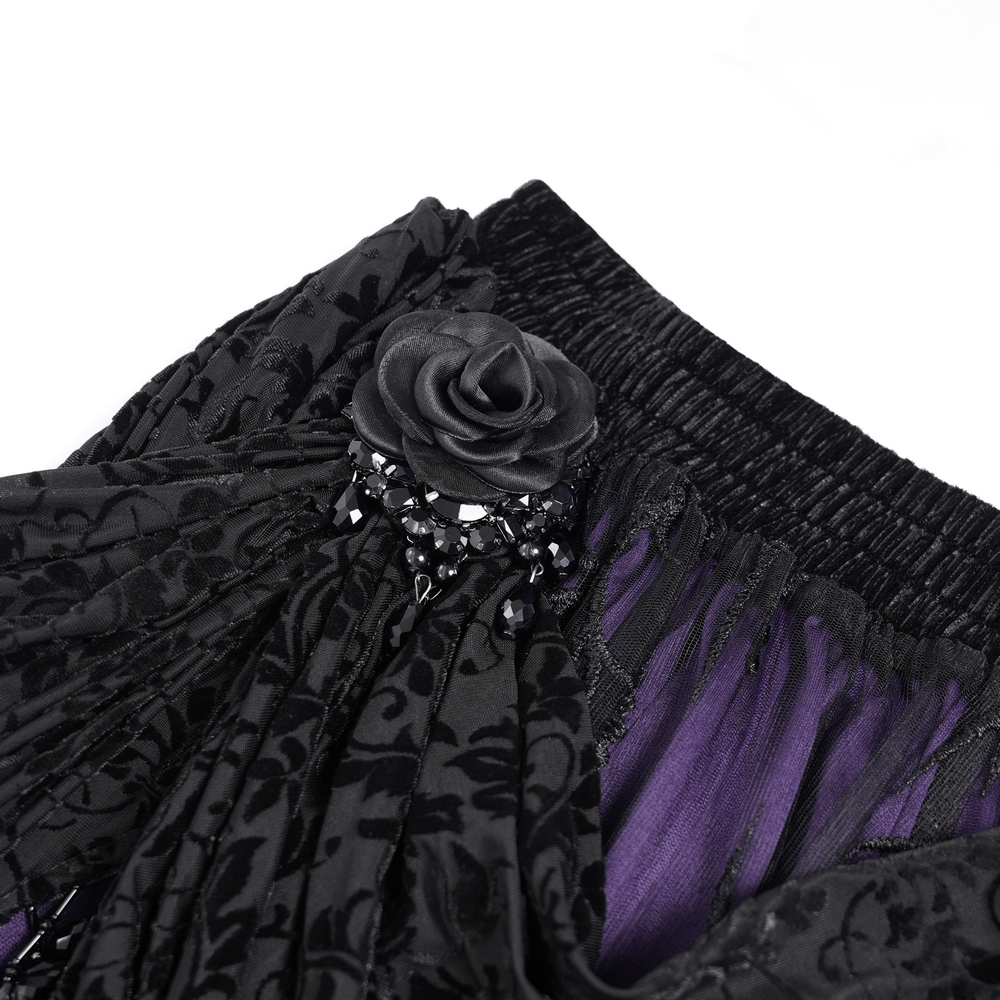 Close-up of black lace skirt featuring a purple interior and floral appliqué with a beaded embellishment on the waistband.