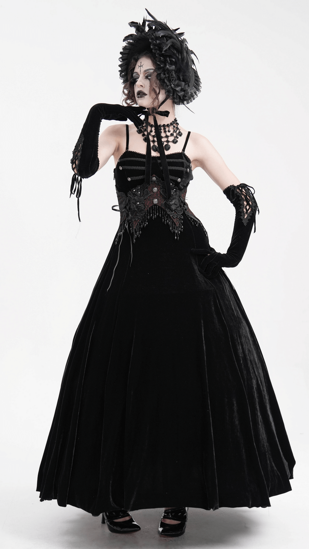 Elegant gothic model in a black velvet gown, adorned with a feathered bonnet and dramatic black gloves.