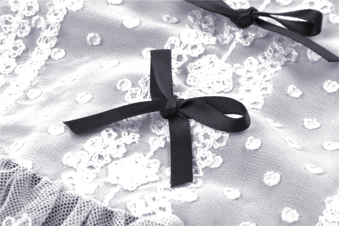 Close-up of black ribbon details on a Victorian black and white dress with lace embellishments.