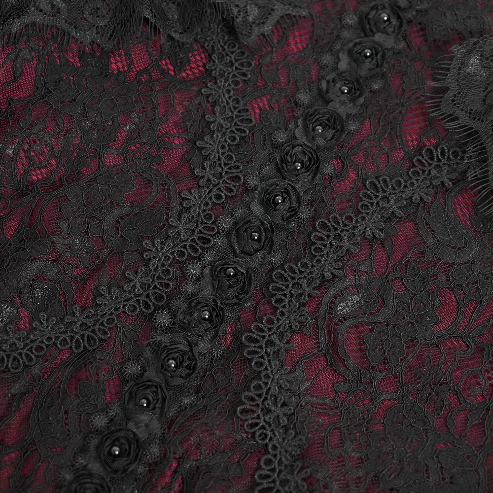 Close-up of intricate black floral lace over rich red fabric with decorative buttons, showcasing Victorian gothic elegance.