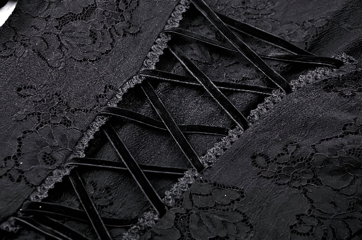 Close-up of Victorian Gothic lace details and corset back of a black mini dress, showcasing elegant floral patterns.