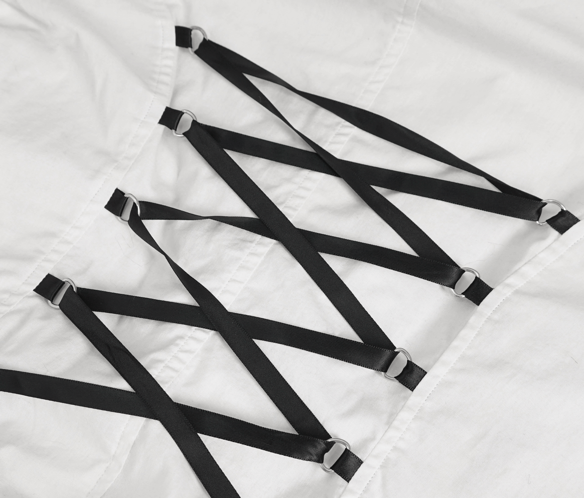 Detail of white fabric with black straps and rings, showcasing a unique lacing design for stylish garments.