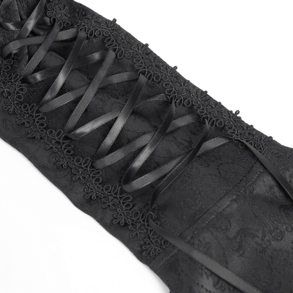 Close-up of black Victorian Gothic blouse lace-up detail with satin ribbons and intricate jacquard fabric.