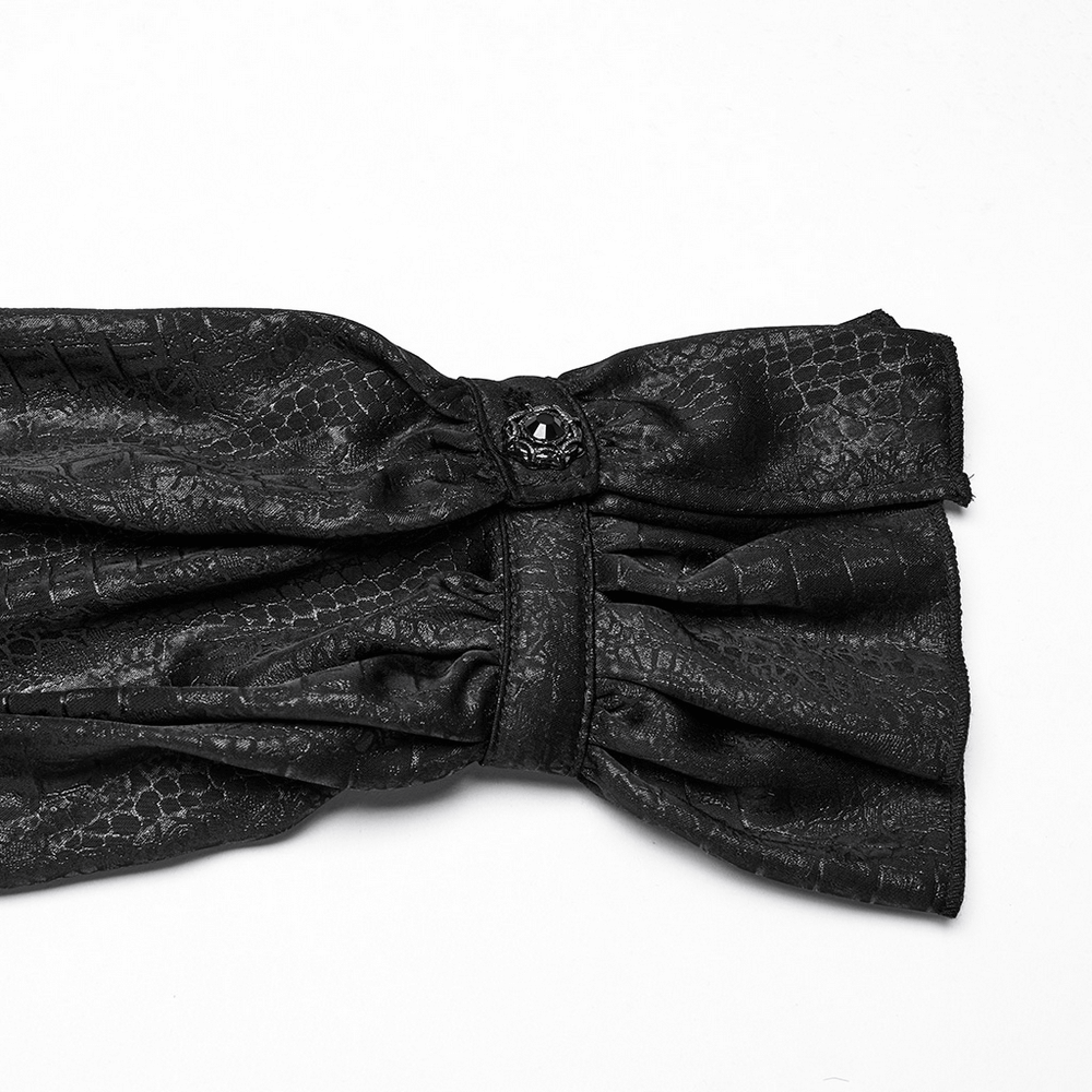 Detail of black faux leather bow with textured pattern, adding gothic elegance to Victorian blouse.
