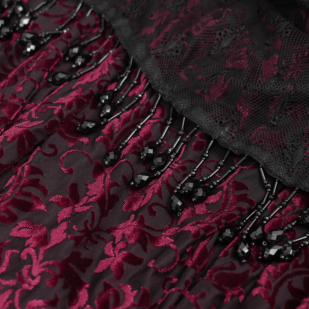 Intricate lace and bead detailing on a dark burgundy gothic skirt with dramatic draped layers and elegant black accents.