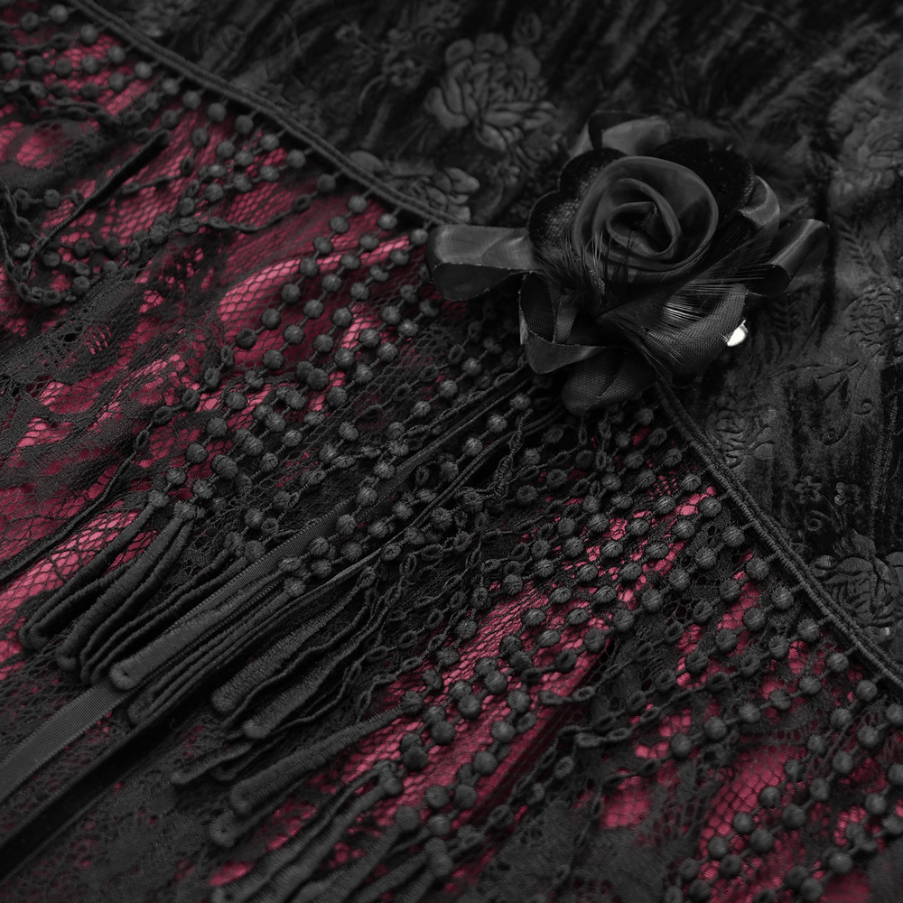 Close-up of a Victorian skirt featuring black lace, tassels, and a rose detail near deep magenta fabric.