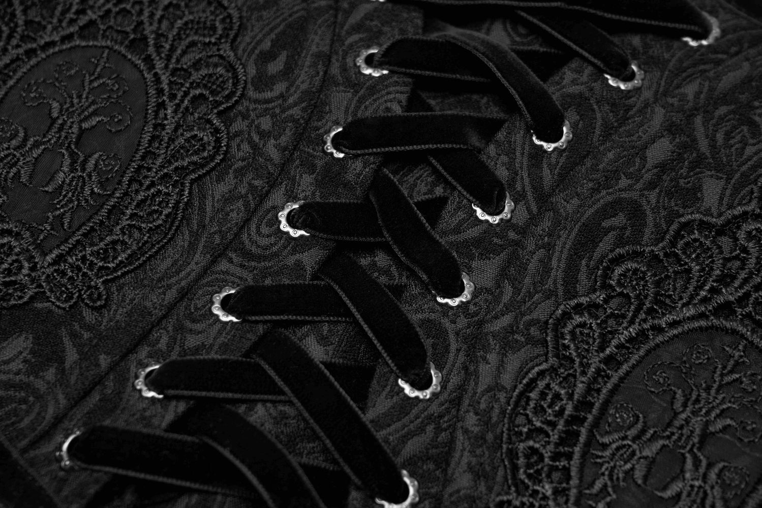 Close-up of Victorian black brocade corset with elegant lace details and ornate eyelet lacing for a gothic look.