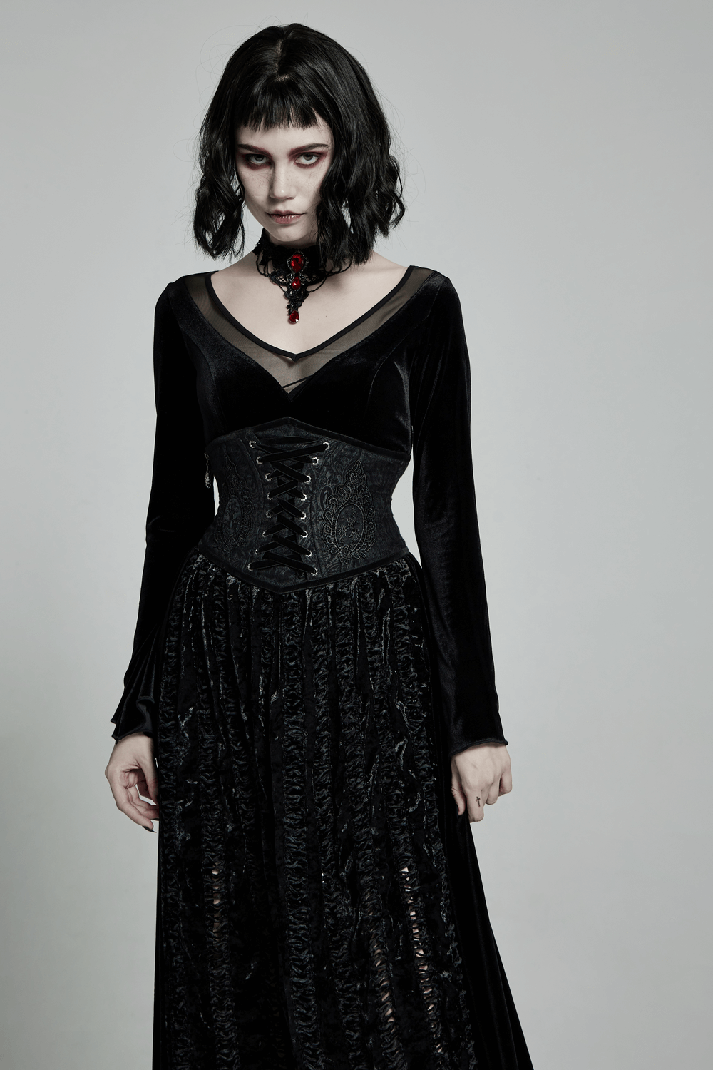 Victorian-inspired black brocade corset with lace details, paired with an elegant black velvet dress.