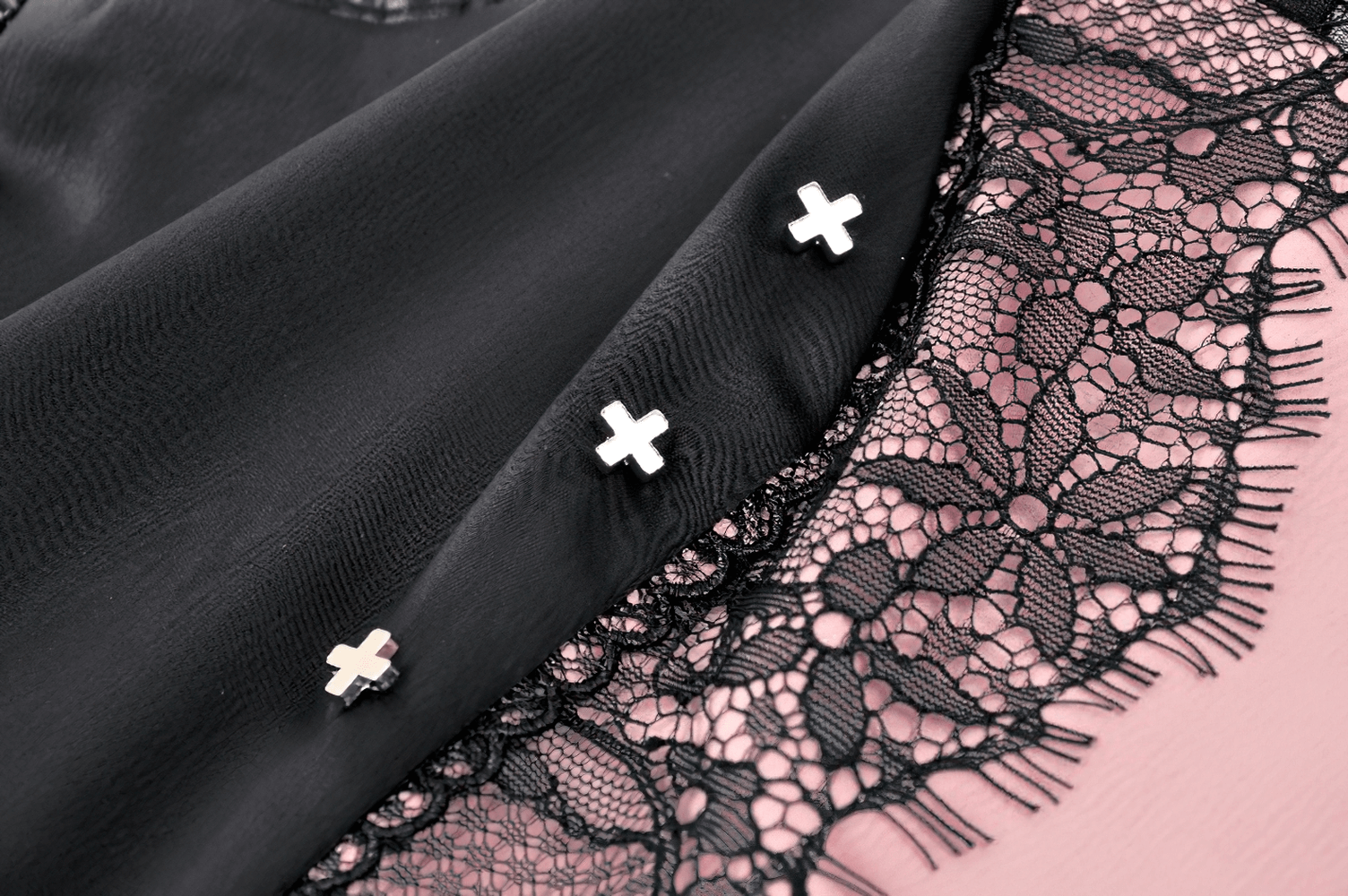 Close-up of black lace with pink underlay and silver accents, showcasing the gothic elegance of a layered mini dress.