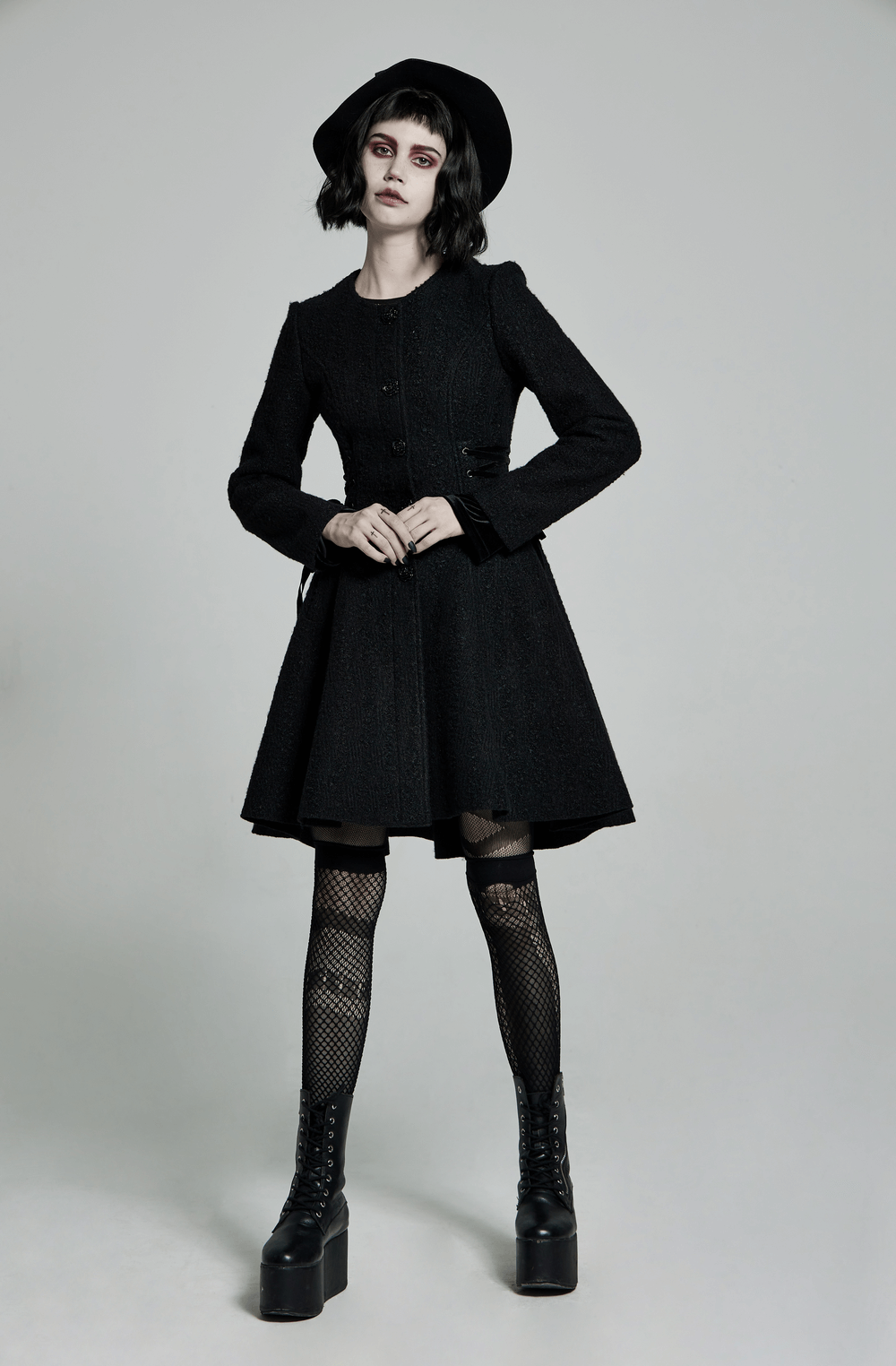 Victorian-inspired goth model wearing a black woollen coat with a flared skirt and stylish accessories.