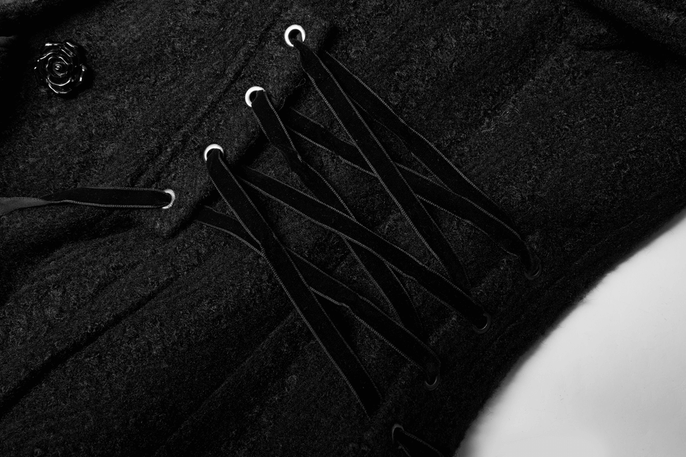 Close-up of a Victorian-inspired woollen coat showcasing elegant rose button and adjustable lace details.