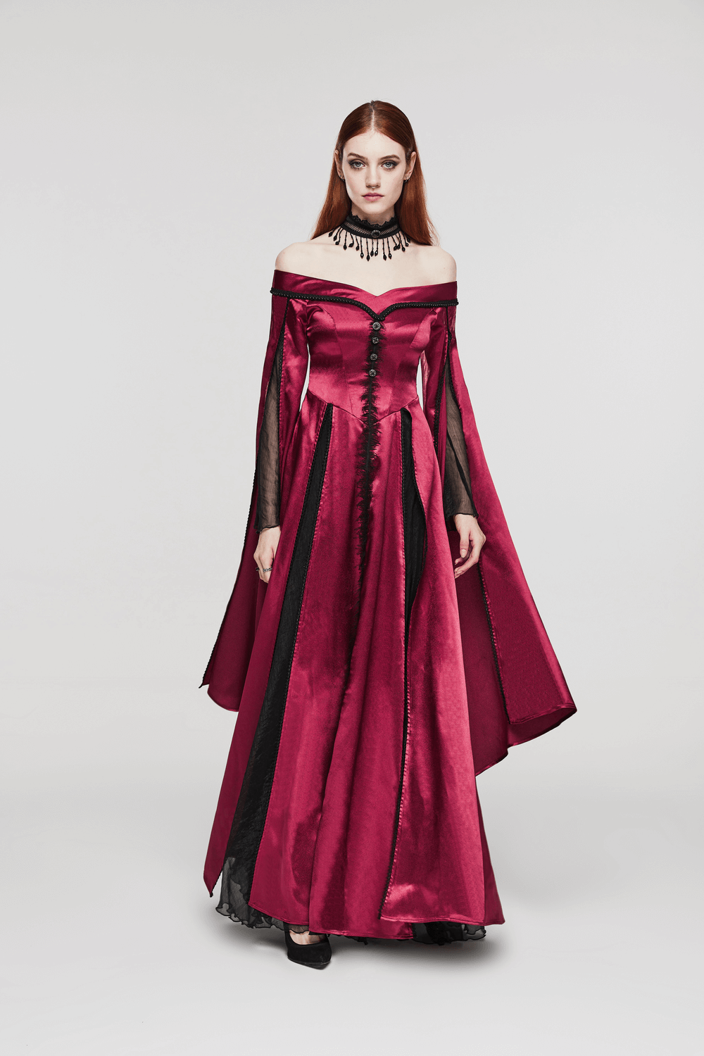 Elegant model in a vintage-inspired red gown with off-shoulder design and dramatic black accents.