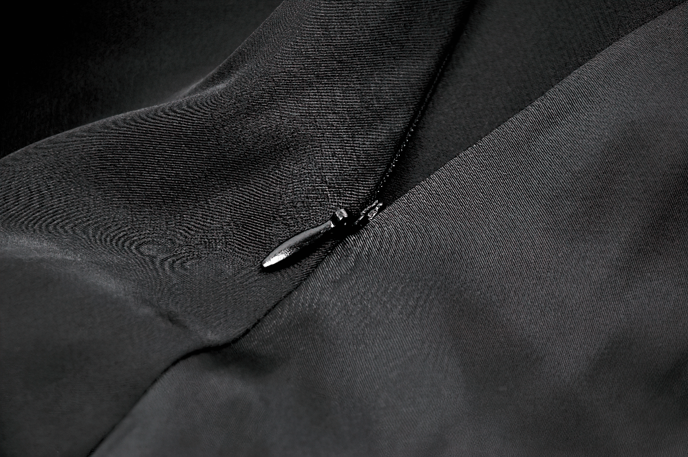 Close-up of a black satin fabric with a delicate zipper detail for a Victorian-inspired dress.