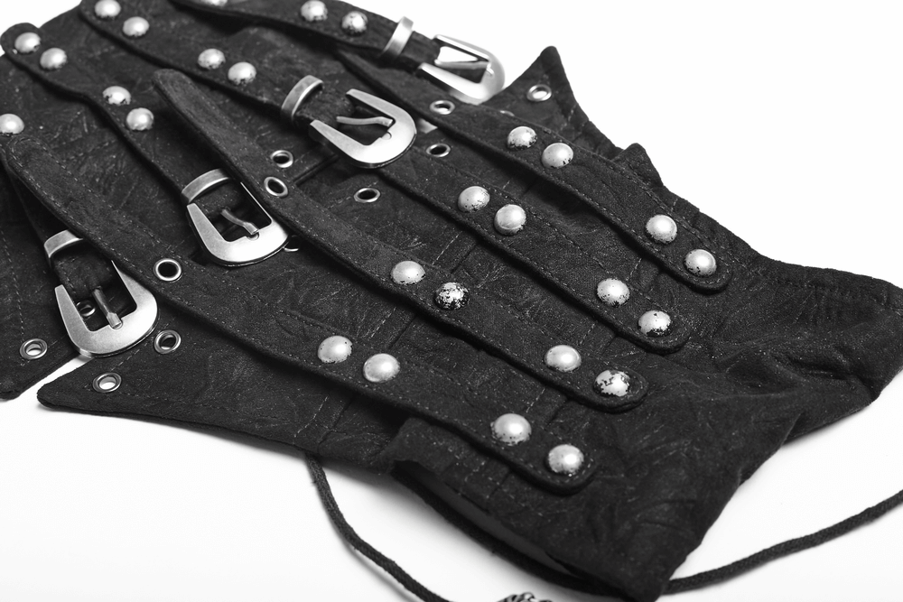 Close-up of a Victorian-inspired studded corset belt with metal buckle loops and rivets on a black fabric.