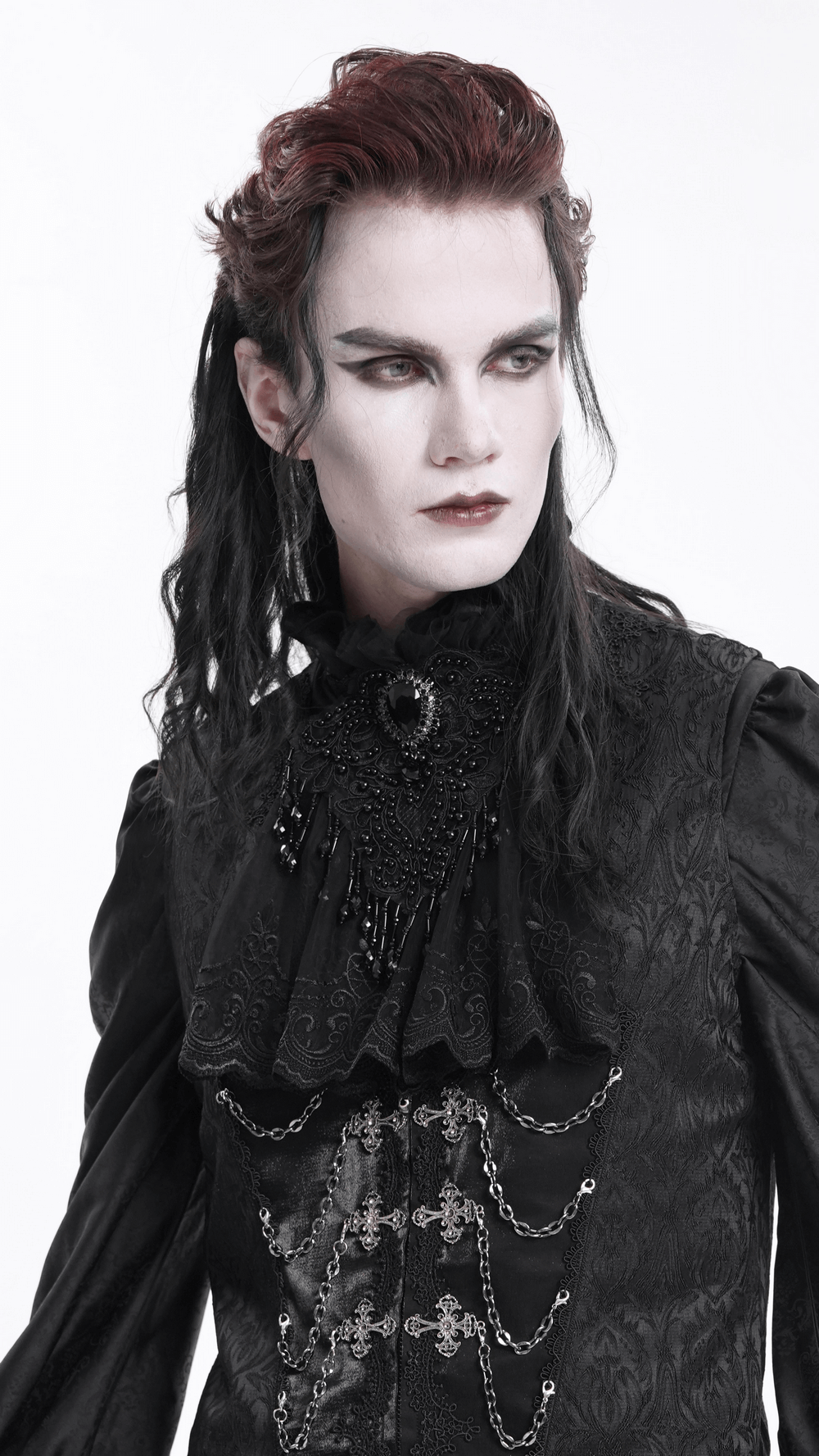 Young man in gothic attire with a black lace collar and intricate beadwork, showcasing a striking fashion statement.