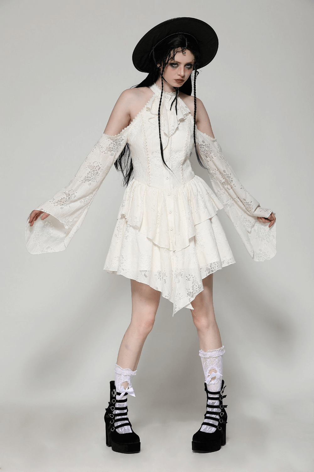 Romantic Victorian lace dress with open shoulders and tiered bell sleeves, paired with chunky platform boots and a wide-brimmed hat.