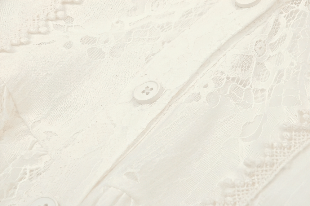 Close-up of intricate lace detailing and buttons on a Victorian lace dress, showcasing romantic beige fabric texture.