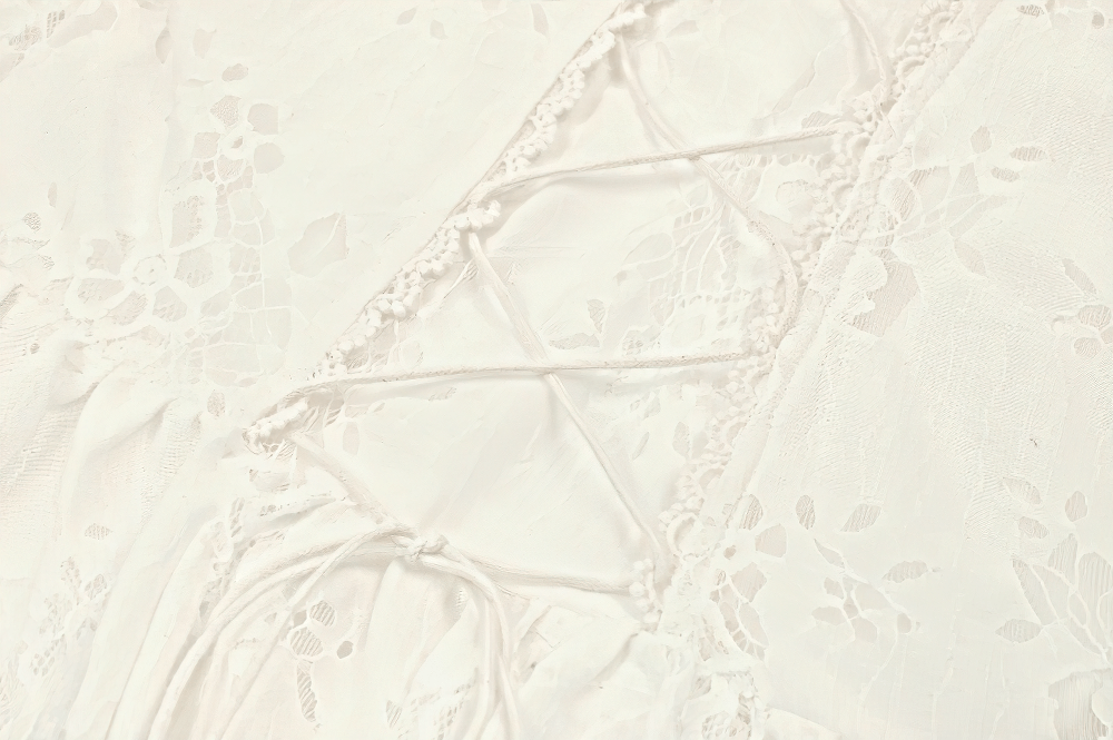 Close-up of intricate lace detailing and corset-style lacing on a romantic white Victorian dress.