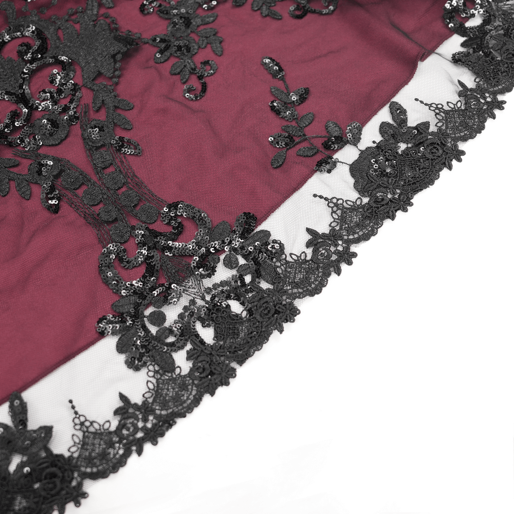 Close-up of burgundy fabric with intricate black lace and beaded embellishments for a gothic Victorian dress.