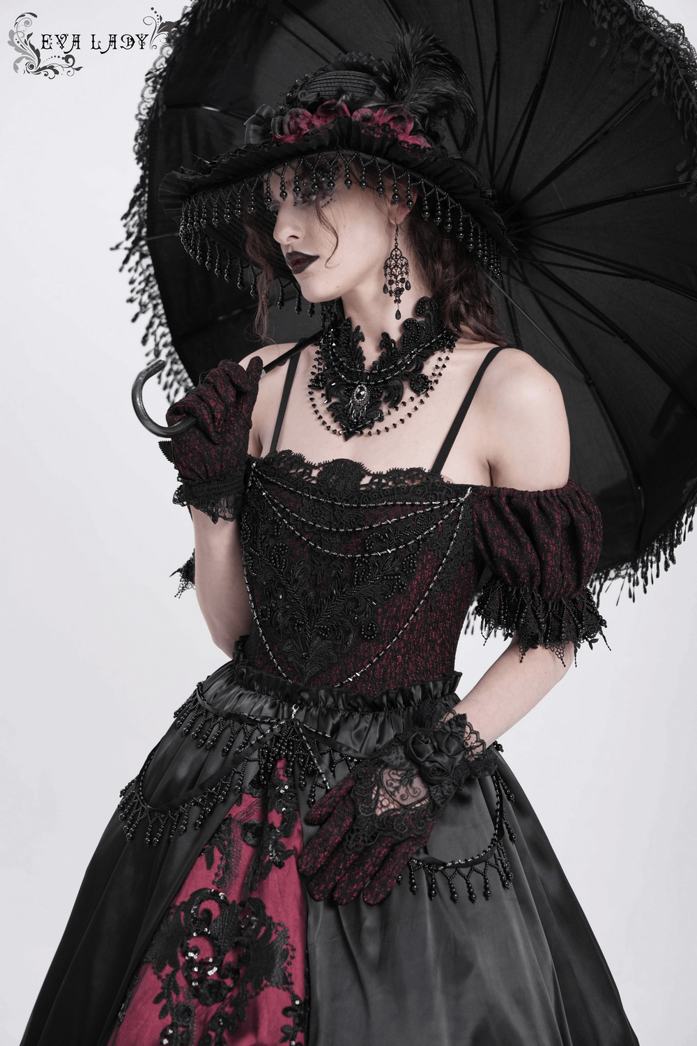 Elegant Victorian lace-up dress in black and burgundy with beaded detail, ruffles, and a stylish black parasol.
