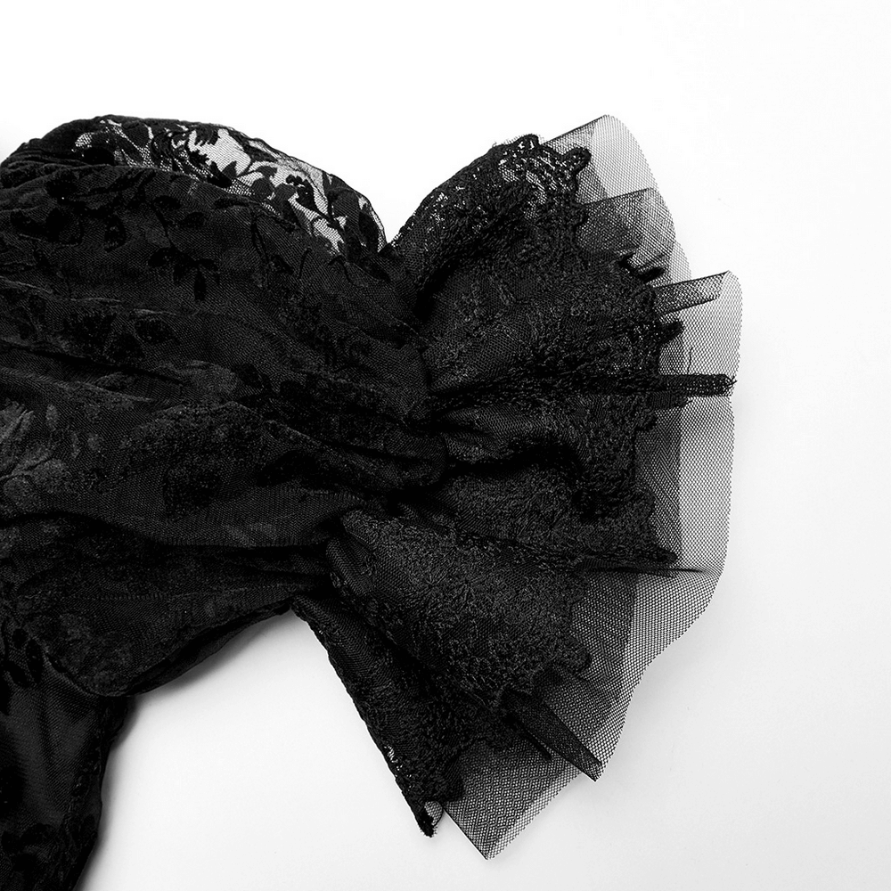 Close-up of luxurious black lace fabric featuring layered frills and intricate Gothic patterns.