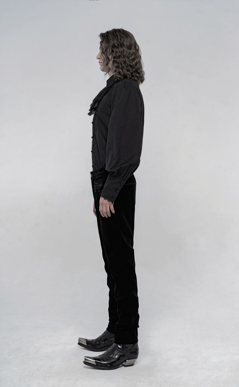 Side view of a model in Victorian style embroidered black velvet gothic trousers, showcasing elegance and craftsmanship.
